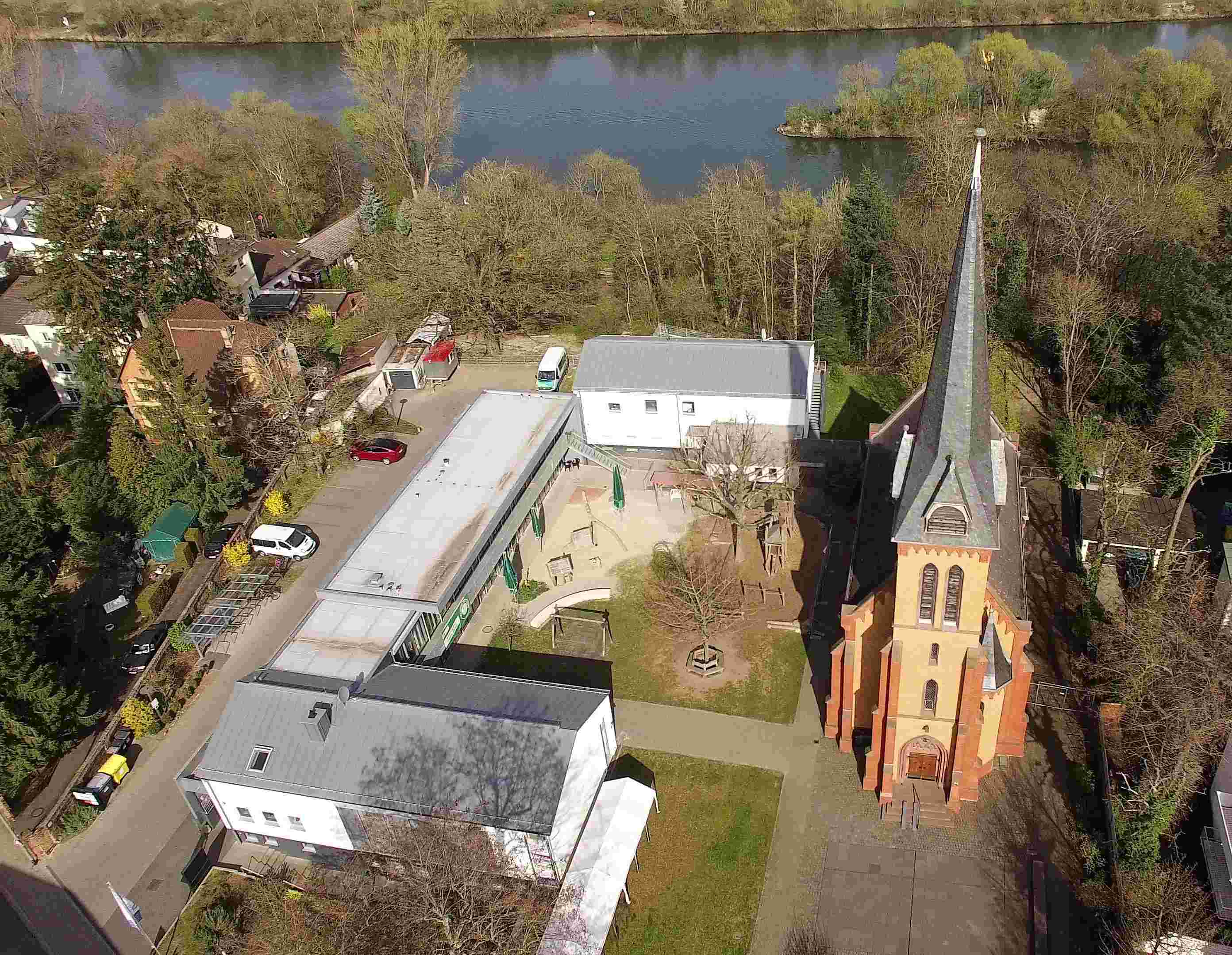 Luftaufnahme der Gebäude: Gemeindezentrum, Kindertagesstätte mit Jugendräumen, Ehemaliges Pfarrhaus wo die Steinheimer Tagespflege und das Zwergennest beheimatet sind.